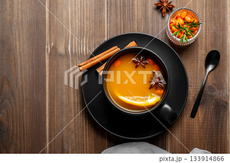 Sea buckthorn herbal tea in a black cup on a wooden background with spices Sea buckthorn herbal tea in a black cup on a wooden background with spices 133914866