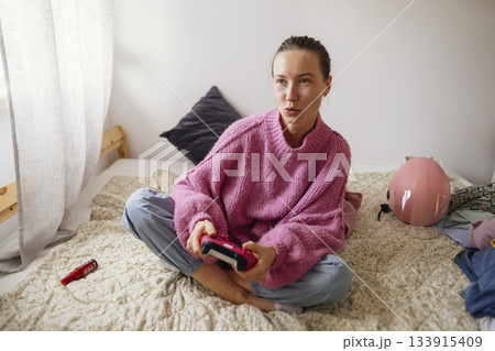 Female gamer relaxing in comfortable setting while focusing on her game 133915409