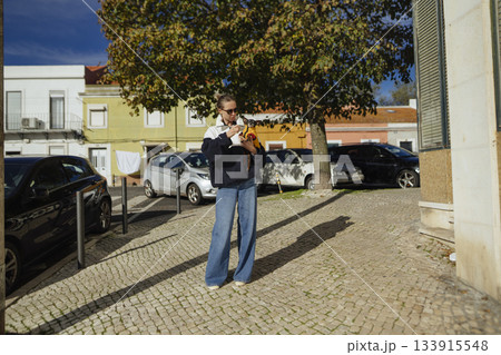 street-style blogger checking phone on sunny cobblestone 133915548