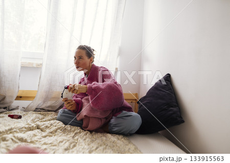 Lady in vibrant attire enjoys relaxing gaming moment indoors Lady in vibrant attire enjoys relaxing gaming moment indoors 133915563