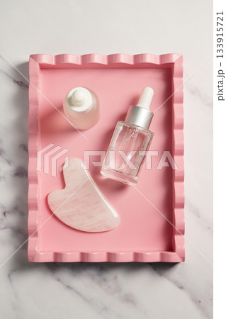 Rose quartz gua sha tool face massage tool and oil bottle, abstract beauty photo Rose quartz gua sha tool face massage tool and oil bottle, abstract beauty photo 133915721