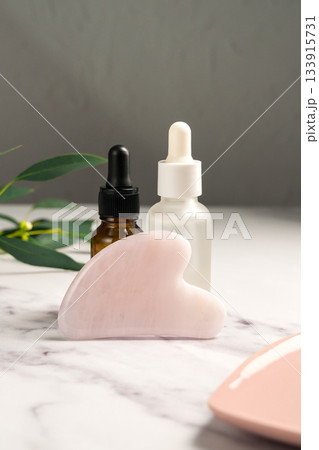 Rose quartz gua sha and oil bottles, abstract beauty photo Rose quartz gua sha and oil bottles, abstract beauty photo 133915731
