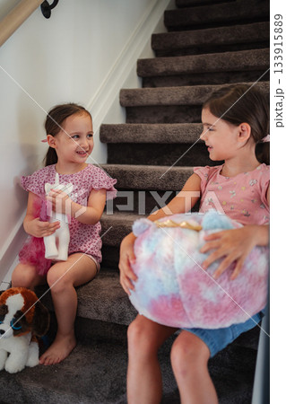 Two young sisters playing with stuffed animals on stairs 133915889