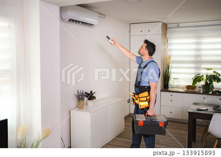 Technician installing or repairing air conditioning system in home 133915893