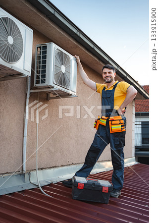 HVAC technician installing an air conditioner on a roof HVAC technician installing an air conditioner on a roof 133915900