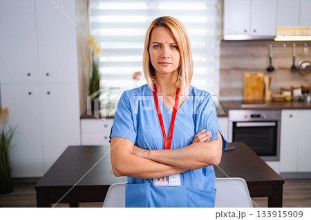 Serious nurse standing with arms crossed in kitchen Serious nurse standing with arms crossed in kitchen 133915909