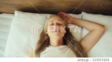 Woman sleeping lying in bed on white soft comfortable pillow in bedroom at home Woman sleeping lying in bed on white soft comfortable pillow in bedroom at home 133915929
