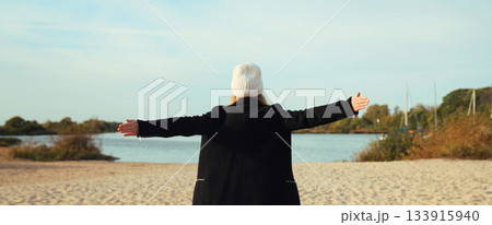 Back view of happy woman on sunny beach, joyful girl enjoying landscape, warm weather on sea coast 133915940