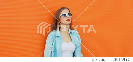 Portrait of modern stylish young woman in white glasses, casual clothing posing on orange background 133915957
