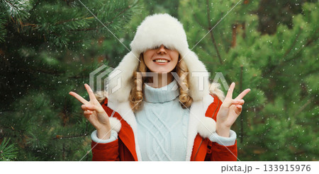 Winter portrait of happy smiling woman having fun enjoys snow against Christmas tree in forest 133915976