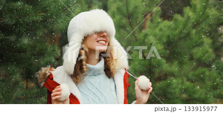 Winter portrait of happy smiling woman having fun enjoys snow against Christmas tree in forest 133915977