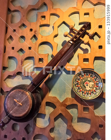 Musical instrument displayed against intricate wooden wall design 133915999