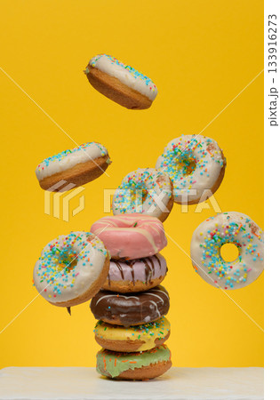 Levitating donuts with sugar sprinkles levitate on a yellow background Levitating donuts with sugar sprinkles levitate on a yellow background 133916273