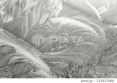 Intricate frost patterns detailed on a window during a cold winter morning Intricate frost patterns detailed on a window during a cold winter morning 133917000