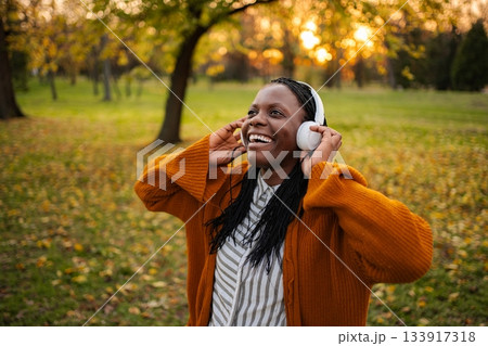 Happy woman enjoying music listening to headphones in park 133917318