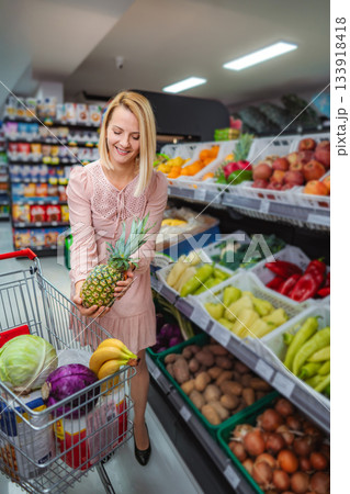 Woman buying fresh pineapple choosing healthy groceries in supermarket 133918418