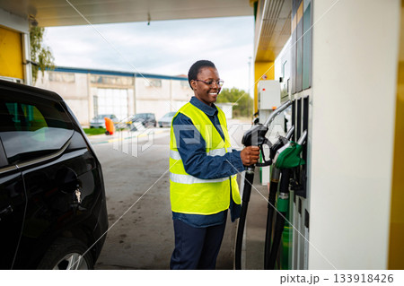 Woman worker smiling while refueling car at gas station 133918426