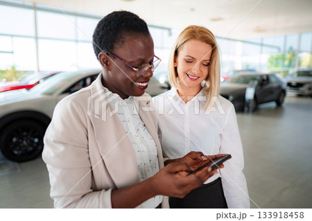 Car salesperson showing customer information on mobile phone 133918458