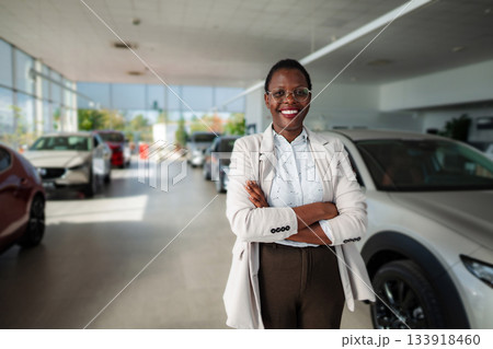 Happy woman sales manager standing in car dealership showroom 133918460