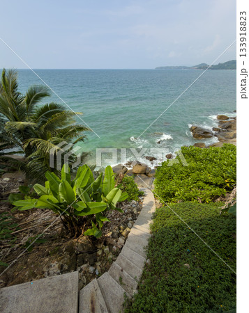 stone staircase leading through tropical trees to the sea and rocky coast, palm trees, surf, azure water 133918823