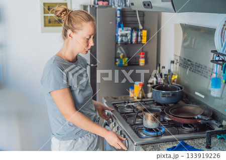 Woman preparing breakfast in a bright home kitchen, enjoying a calm morning routine and creating a warm start to the day. Healthy lifestyle, home cooking and cozy domestic living concept showing 133919226