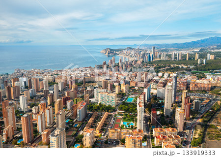 Aerial view of Benidorm skyline filled with high rise towers along the coast. Bright sunny weather and clear sea make this Spanish city a favorite tourist destination. Aerial view of Benidorm skyline filled with high rise towers along the coast. Bright sunny weather and clear sea make this Spanish city a favorite tourist destination. 133919333
