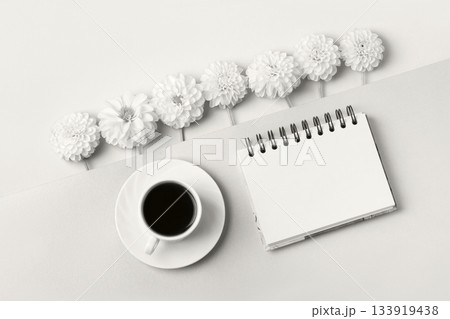 Demonstrating the colors of 2026 - Cloud Dancer. Opened blank notepad with flowers and a cup of coffee. Festive office desktop concept. Demonstrating the colors of 2026 - Cloud Dancer. Opened blank notepad with flowers and a cup of coffee. Festive office desktop concept. 133919438