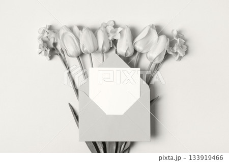 Demonstrating the colors of 2026 - Cloud Dancer. Gray envelope with clean white sheet of paper for your text and spring flowers tulips on white background. Invitation to the holidays. Flat lay. Demonstrating the colors of 2026 - Cloud Dancer. Gray envelope with clean white sheet of paper for your text and spring flowers tulips on white background. Invitation to the holidays. Flat lay. 133919466