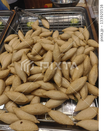 Fried fish cake pile snack street food market stall golden brown oval shape crispy texture savory aroma Fried fish cake pile snack street food market stall golden brown oval shape crispy texture savory aroma 133920516