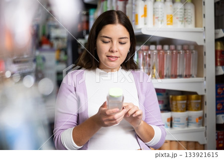 Young woman is choosing new conditioner in hair care store 133921615