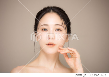髪の毛がアップ背景がベージュの使いやすい美容やスキンケアの美しい女性のイメージ　クローズアップ 133921693