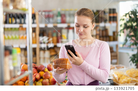 Female buyer scans QR code on cheese label in grocery store Female buyer scans QR code on cheese label in grocery store 133921705