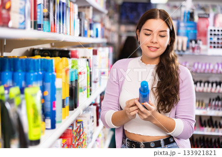 Portrait of positive female buying hair conditioner or mousse in hair care products shop Portrait of positive female buying hair conditioner or mousse in hair care products shop 133921821
