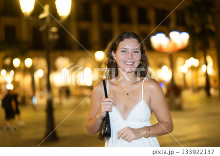 In night, young smiling girl walks along city street Placa Real In night, young smiling girl walks along city street Placa Real 133922137
