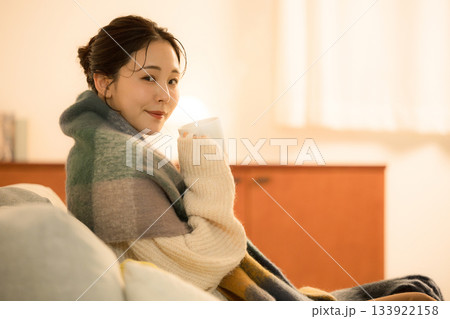 夜の灯りの部屋でホットドリンクを飲む若い女性 女性の冬イメージ 白熱灯のあたたかいカメラ目線 夜の灯りの部屋でホットドリンクを飲む若い女性 女性の冬イメージ 白熱灯のあたたかいカメラ目線 133922158