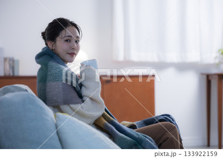 夜の灯りの部屋でホットドリンクを飲む若い女性　女性の冬イメージ　カメラ目線 133922159