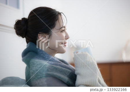 夜の灯りの部屋でホットドリンクを飲む若い女性　女性の冬イメージ 133922166