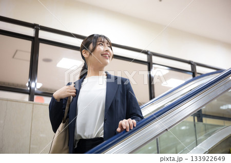 空港や駅のエスカレーターを降りるスーツ姿のキャリア女性のビジネス交通機関移動シーン　振り返る	 133922649