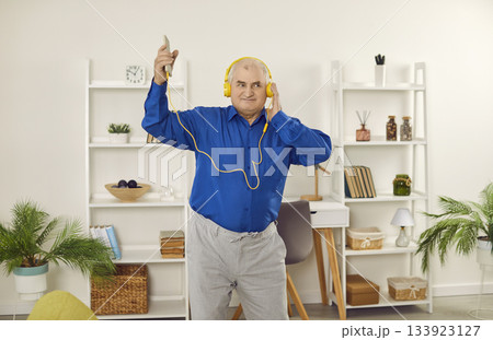Happy senior man in headphones listening to music using smartphone 133923127
