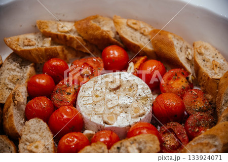 Camembert cheese baked with tomatoes and baguette, herbs and garlic. An excellent appetizer for wine. View from above. Camembert cheese baked with tomatoes and baguette, herbs and garlic. An excellent appetizer for wine. View from above. 133924071