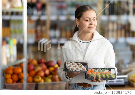 Young woman choosing packaged sushi and rolls Young woman choosing packaged sushi and rolls 133924176