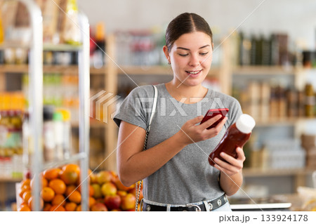 Young woman scanning qr code for ketchup Young woman scanning qr code for ketchup 133924178