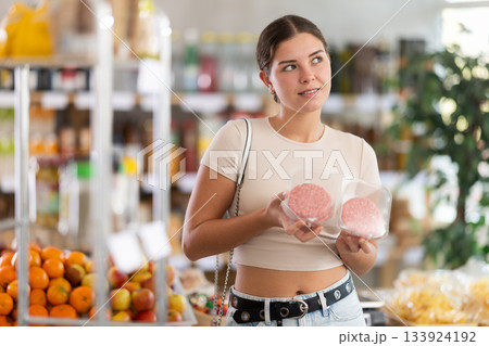 Young woman choosing hamburger in grocery store Young woman choosing hamburger in grocery store 133924192