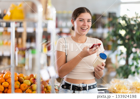 Young woman scanning qr code for mayonnaise Young woman scanning qr code for mayonnaise 133924198