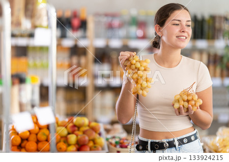 Young woman choosing grapes in grocery store 133924215