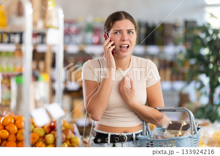 Angry young woman speak by phone in sales area of store 133924216