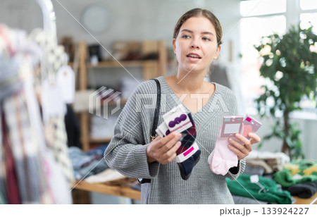 Uncertain young girl choosing socks in clothing store Uncertain young girl choosing socks in clothing store 133924227