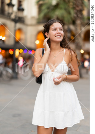 young woman walks through the evening streets of Barcelona 133924346