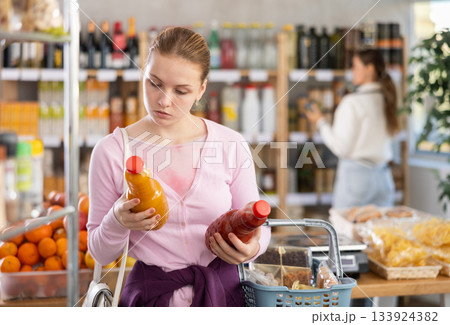 woman chooses juices against the background of buyers woman chooses juices against the background of buyers 133924382