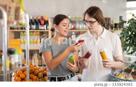 In shop youth spouses scan QR code and take reading smoothie package bottle using phone camera In shop youth spouses scan QR code and take reading smoothie package bottle using phone camera 133924383